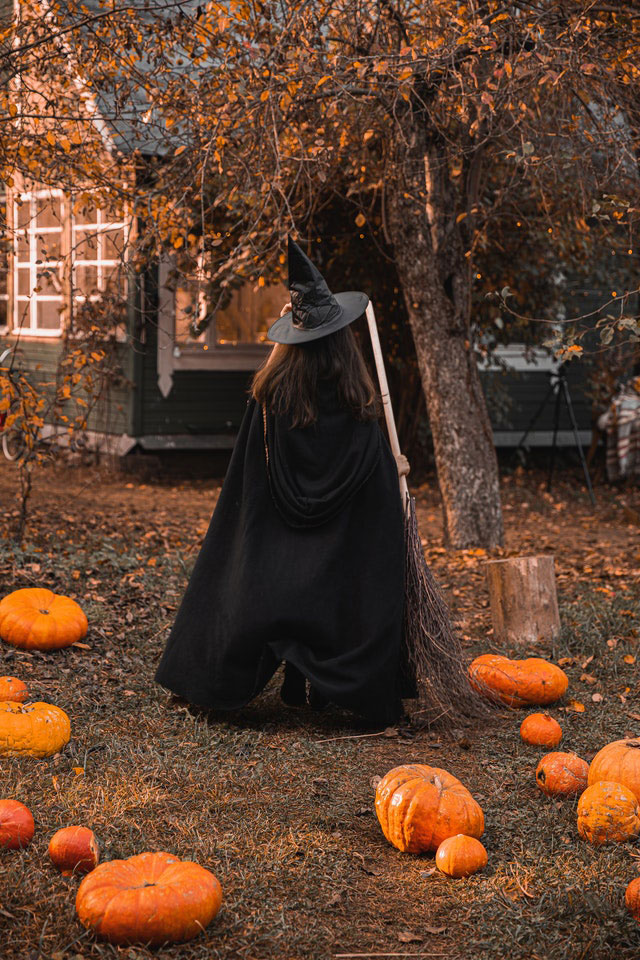 femme déguisée en sorcière avec citrouilles sur son terrain pour l'Halloween