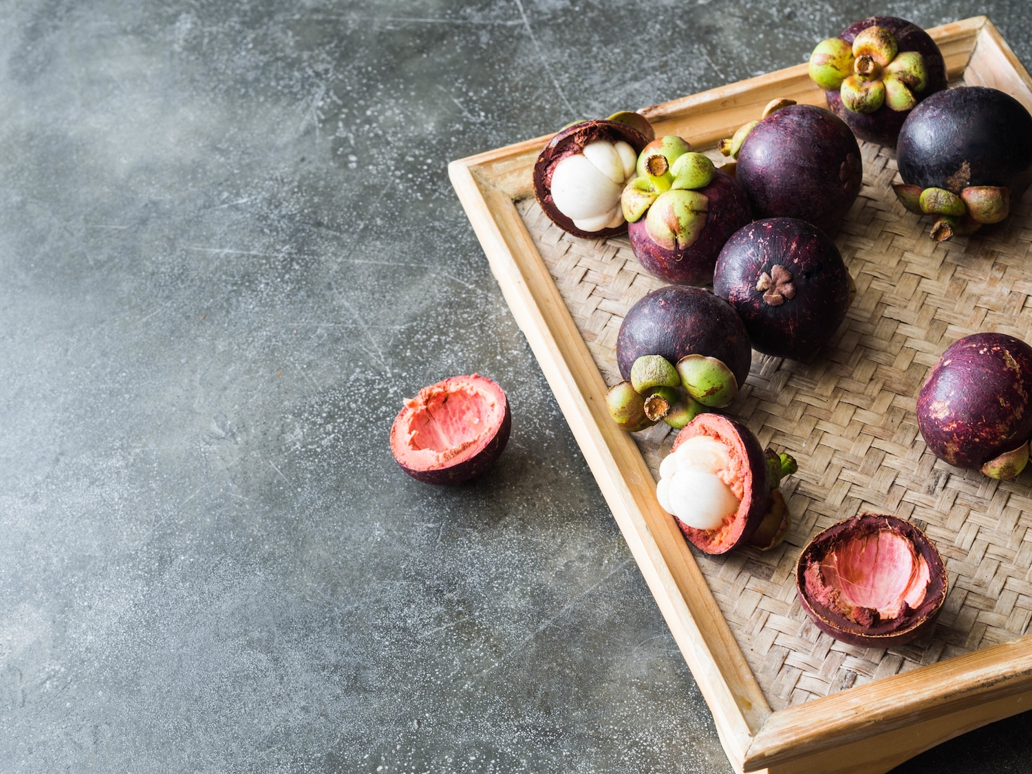 Thai queen of fruits - Mangosteen is  Organic fruit on the wooden tray. Fresh mangosteens on grey background. Selective focus. Copy space