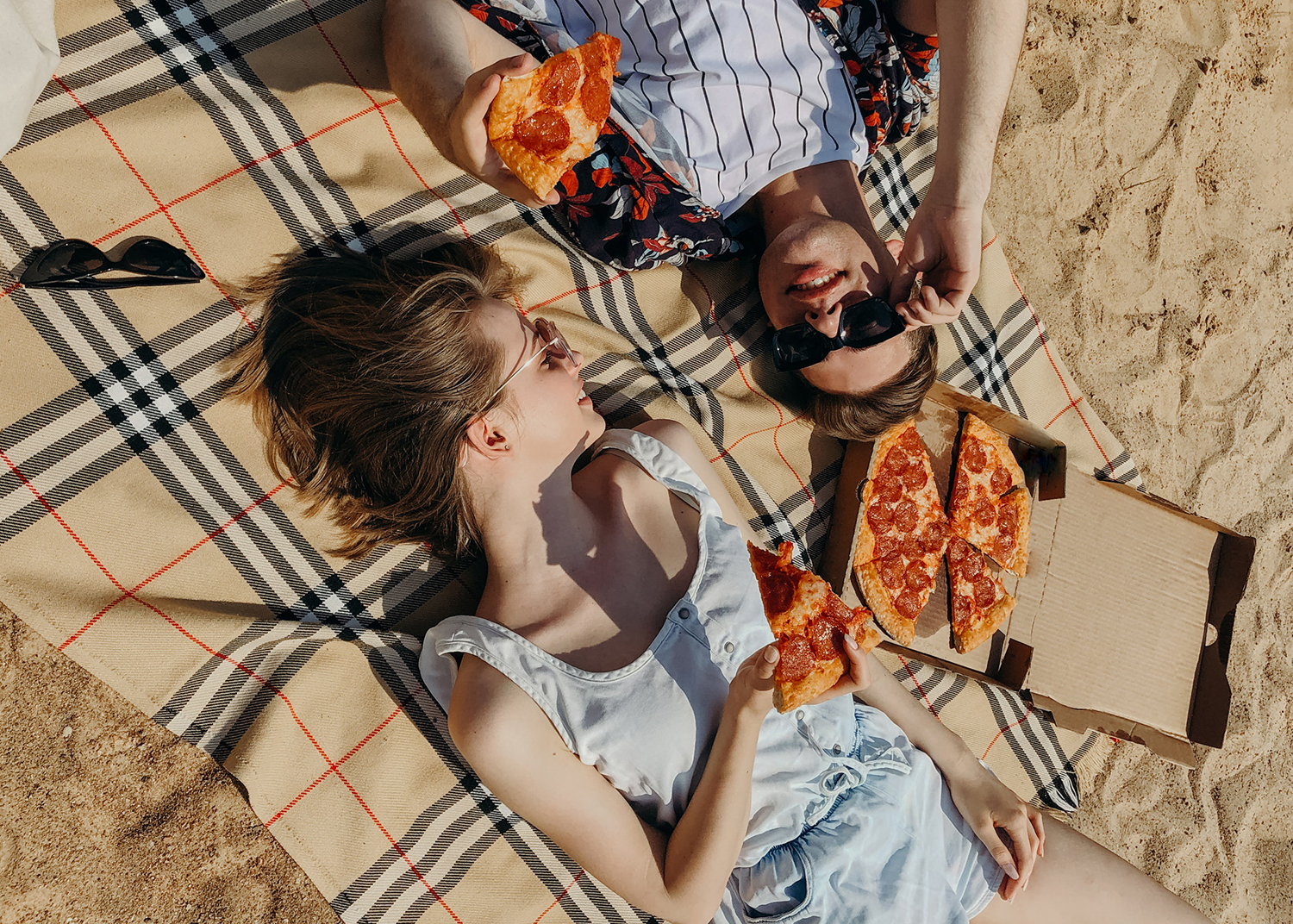 2 jeunes femmes qui mangent de la pizza sur la plage