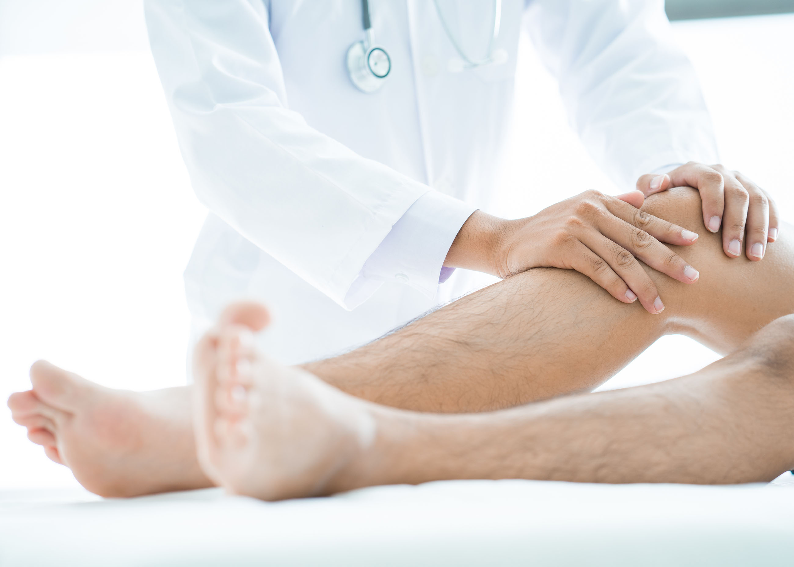 Close-up of male physiotherapist massaging the leg of patient in a physio room.