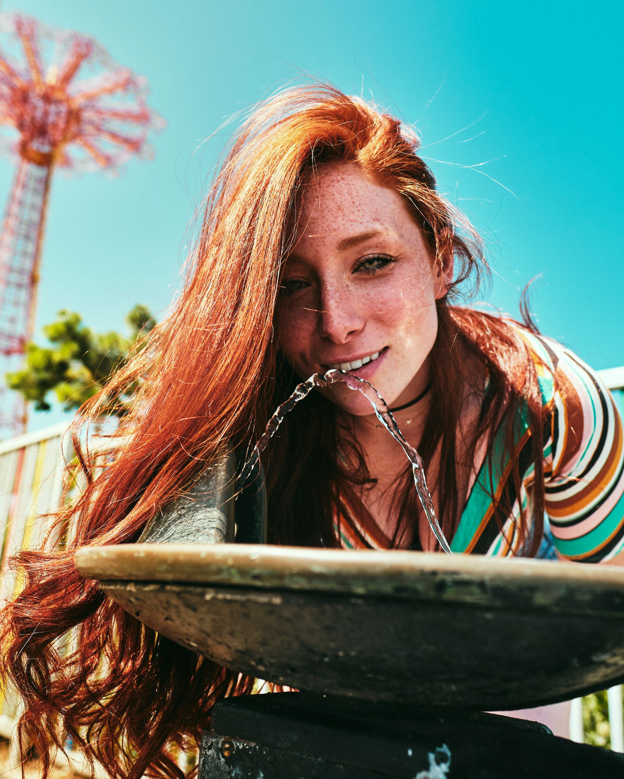 femme rousse boit de l'eau et tente d'éviter coup de soleil