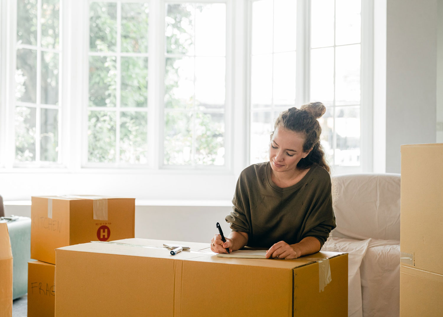 jeune femme écrit sur boite en préparation d'un déménagement