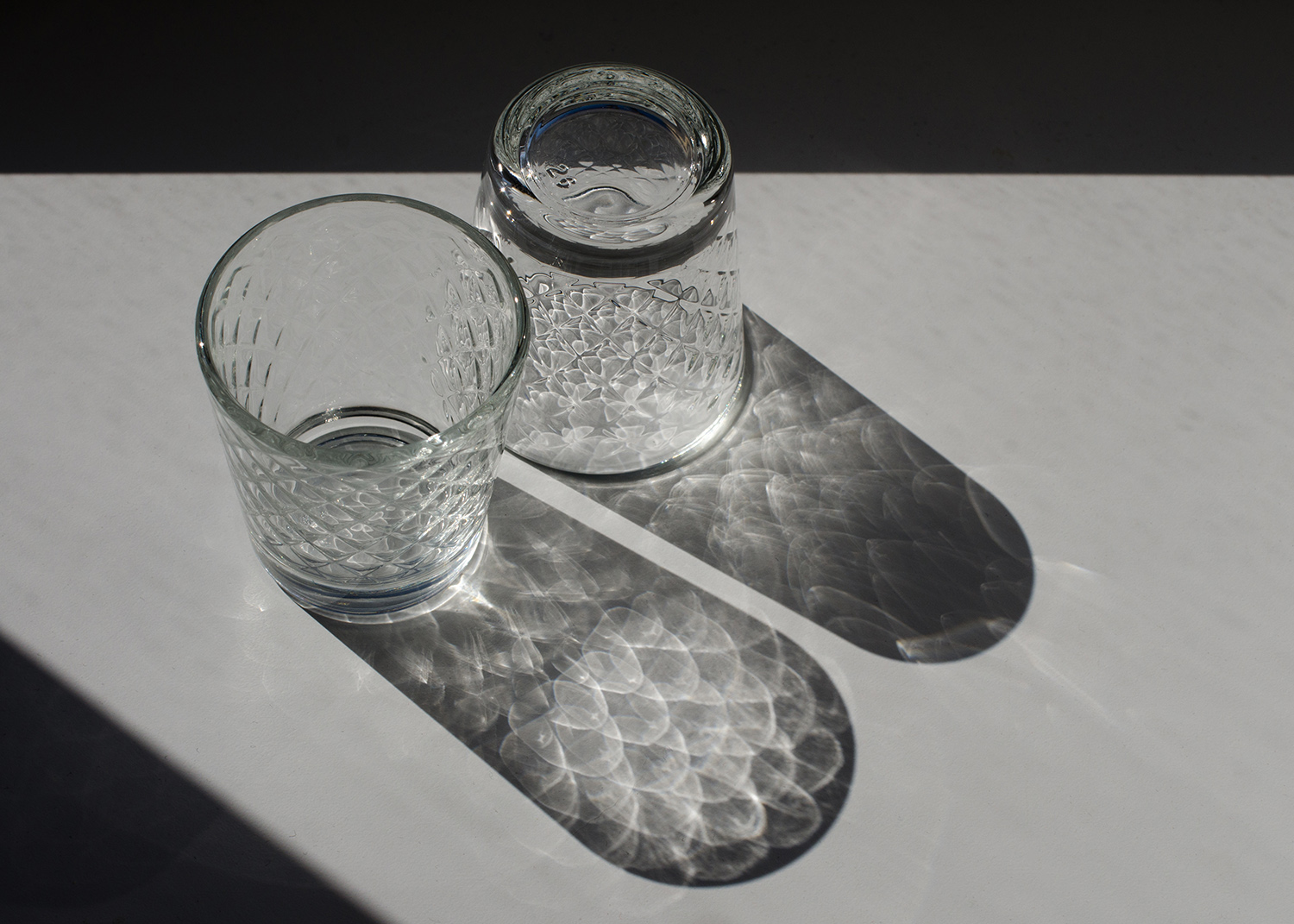 two glass shot glasses with shadows