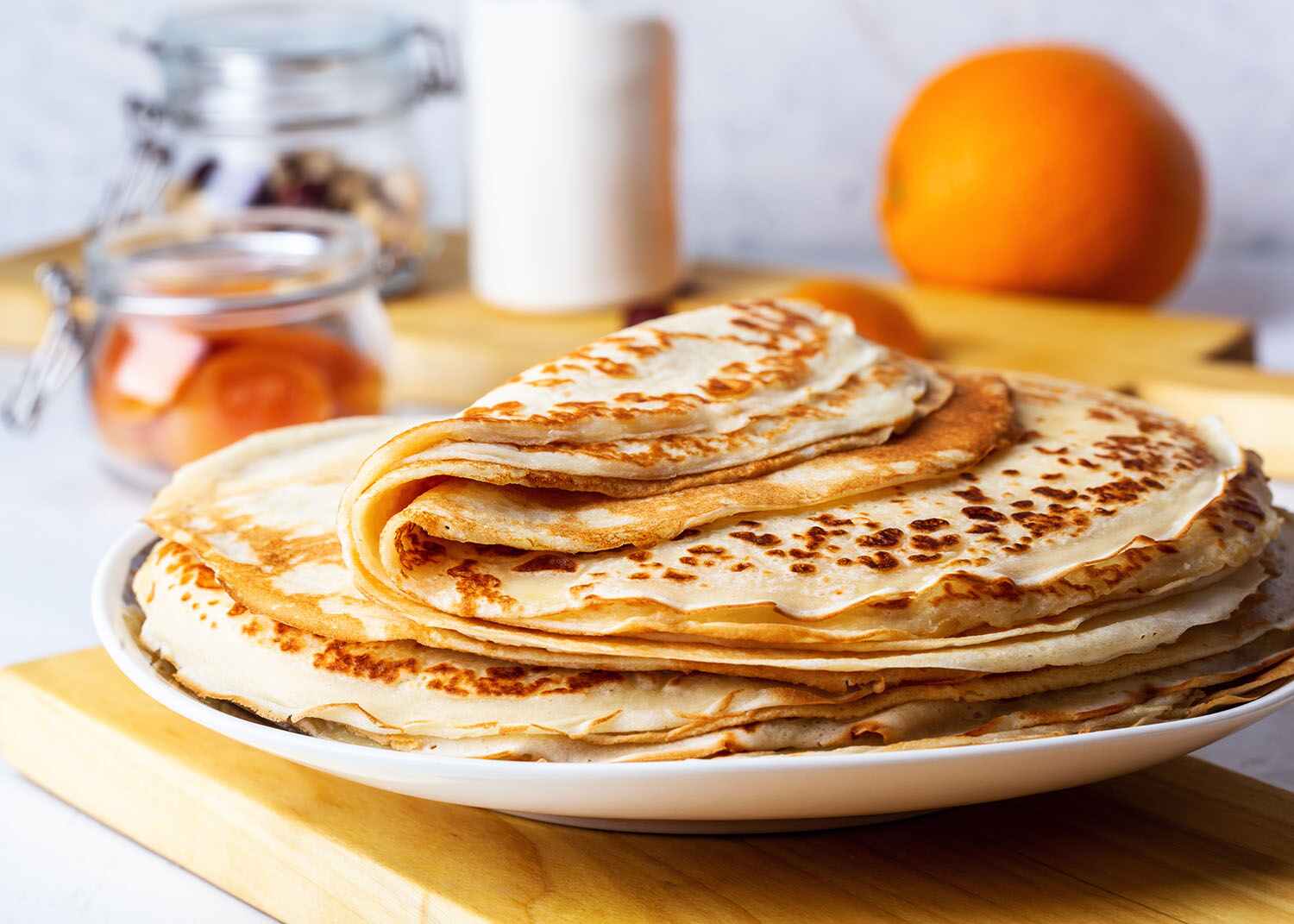 Thin pancakes on white rustic table, ingredients, making blini, domestic kitchen and crepes