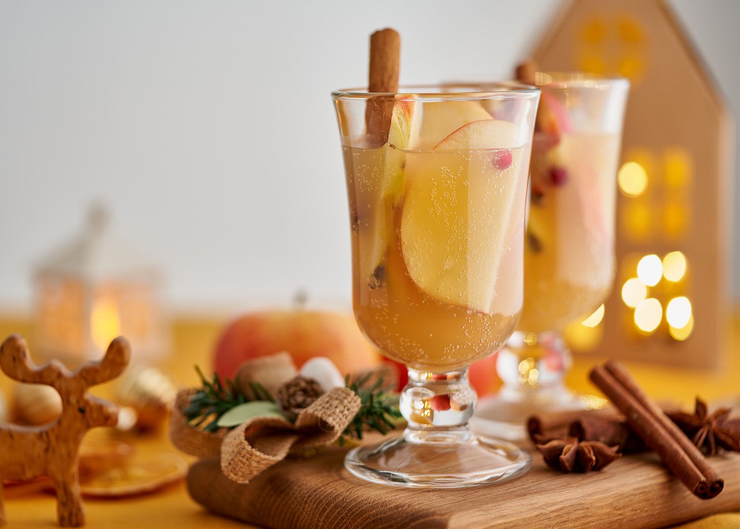 Winter white mulled wine punch. Xmas decor. Colorful grog beverage. Christmas apple cider toddy. Seasonal alcohol winter drink. Advent blurred bokeh garland background, selective focus, copy space