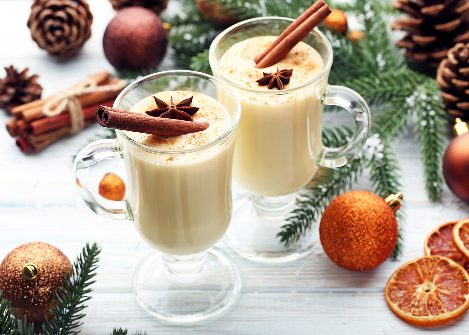 Eggnog in glasses with cinamon and star anise on wooden table