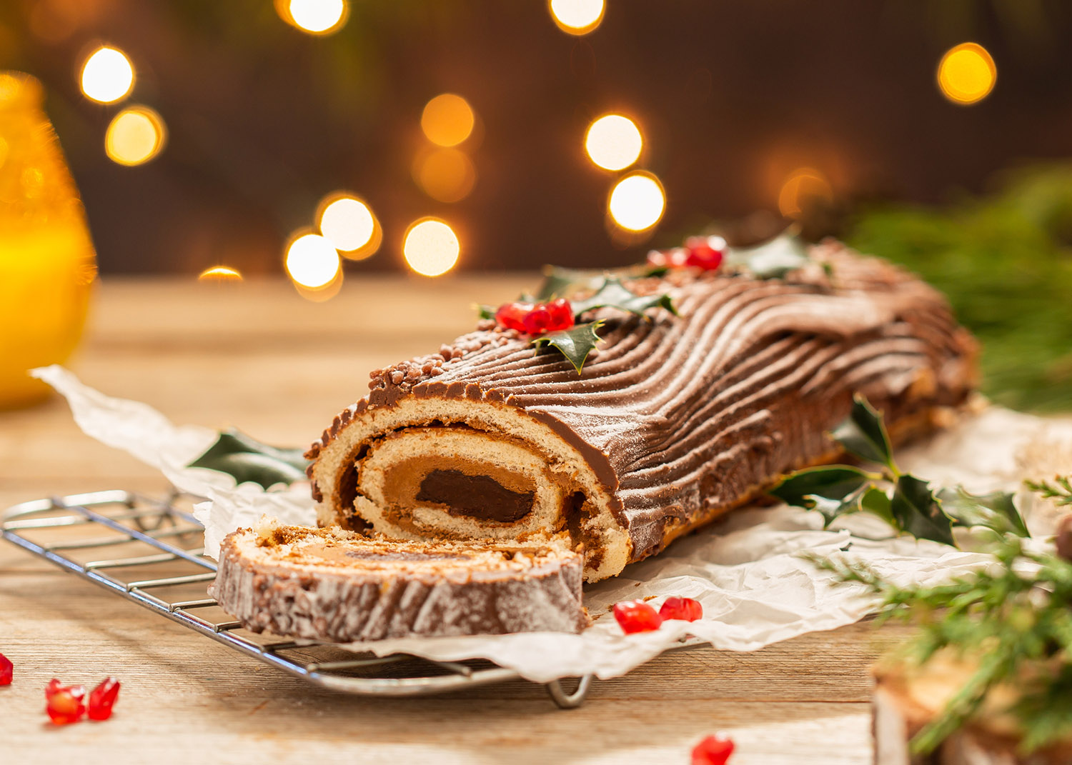 Traditional Christmas cake, chocolate Yule log on a rustic table with festive holiday decorations and lights