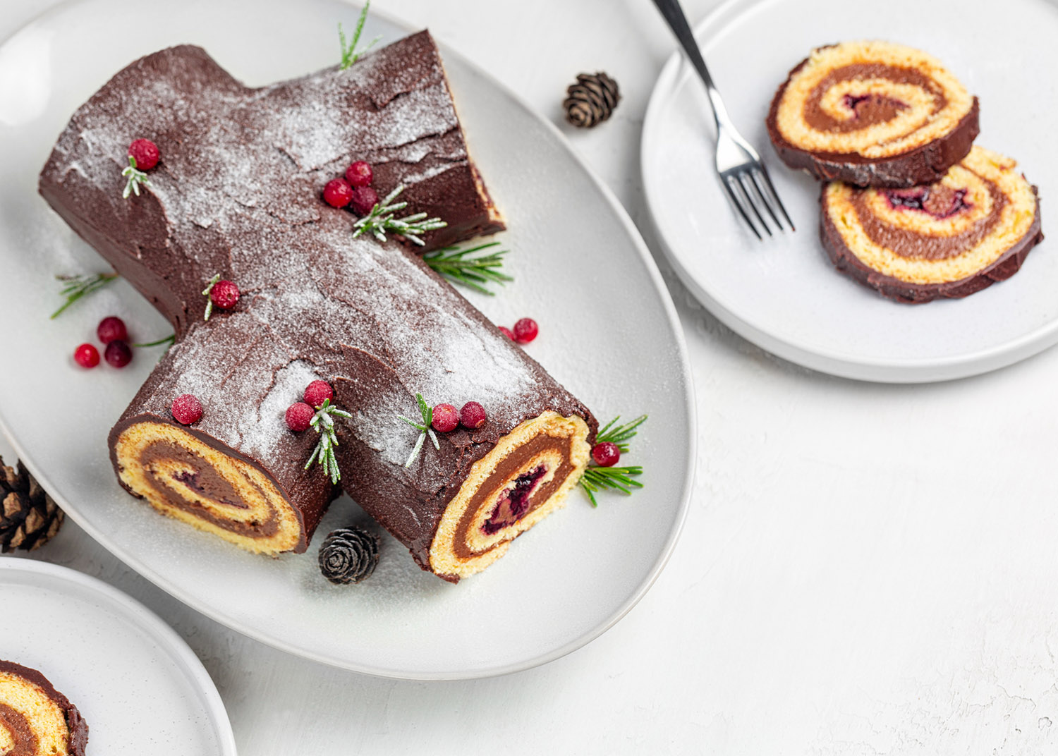 Traditional homemade Christmas cake. Yule log or Buche de Noel. Sponge cake with chocolate cream, ganache, decorated with cranberries. Sliced food, ready for eat.