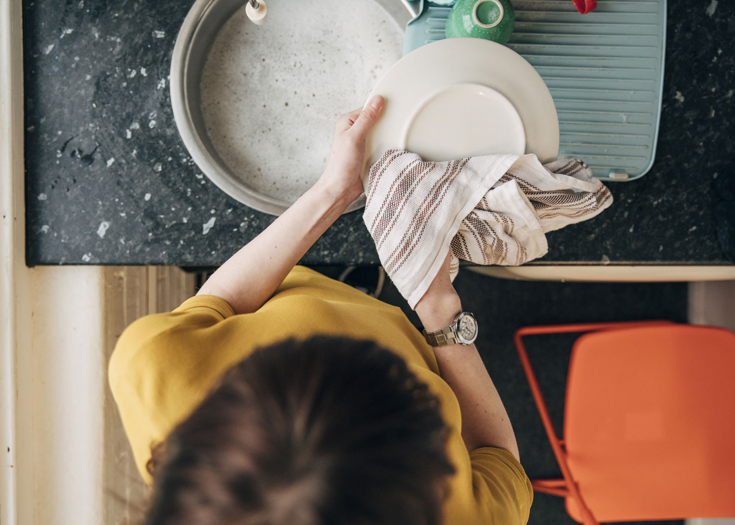femme essuie la vaisselle avec un linge à vaisselle