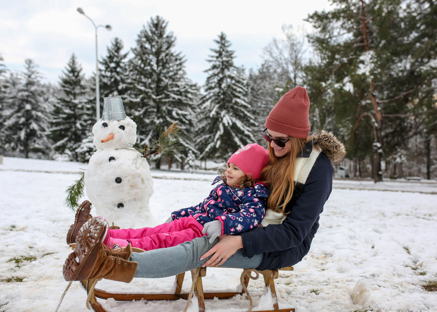 mère avec sa fille se reposent à côté d'un bonhomme de neige