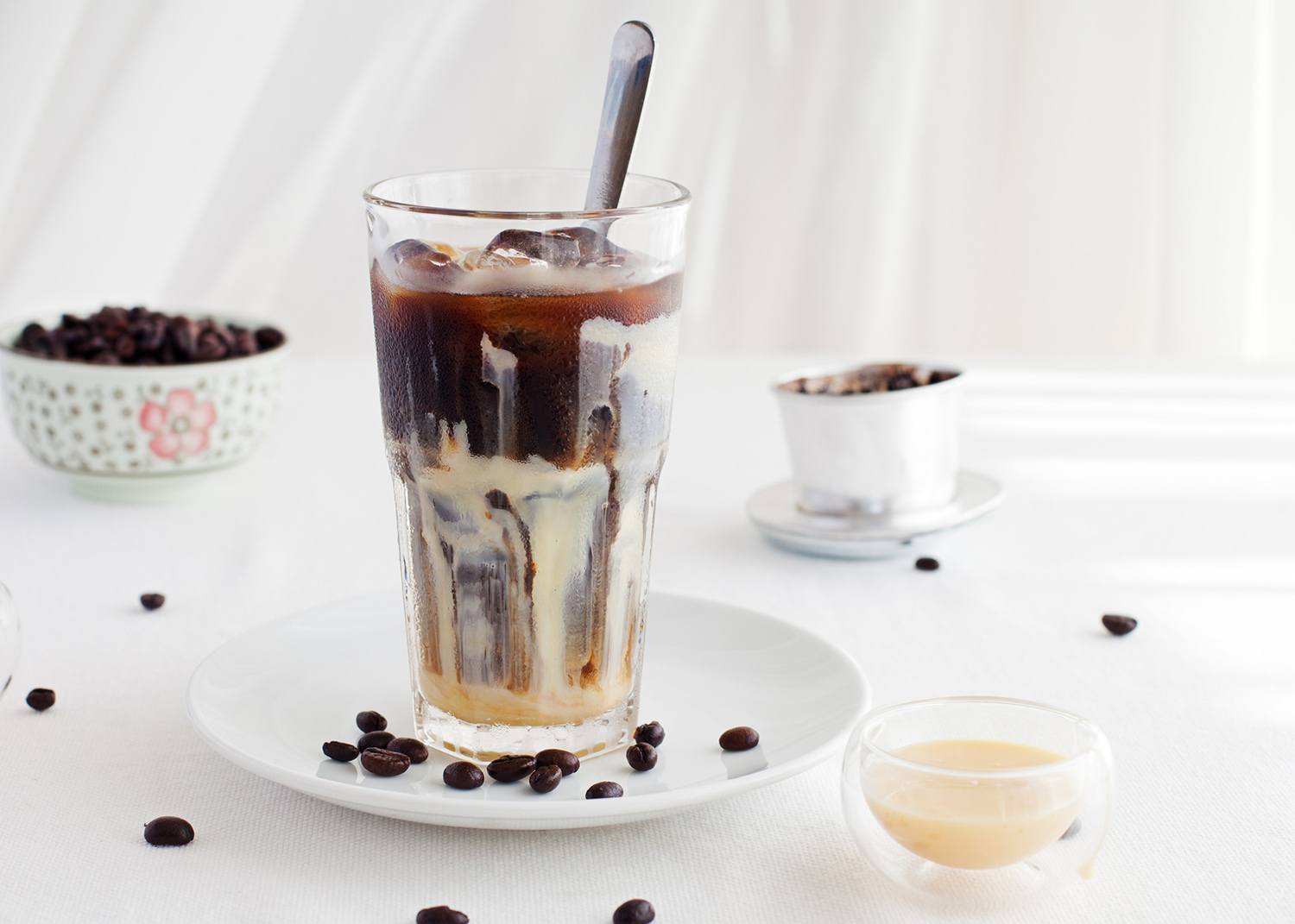 Ice coffee with condensed milk, traditional Vietnamese, Thai coffee with coffee beans on a white plate background