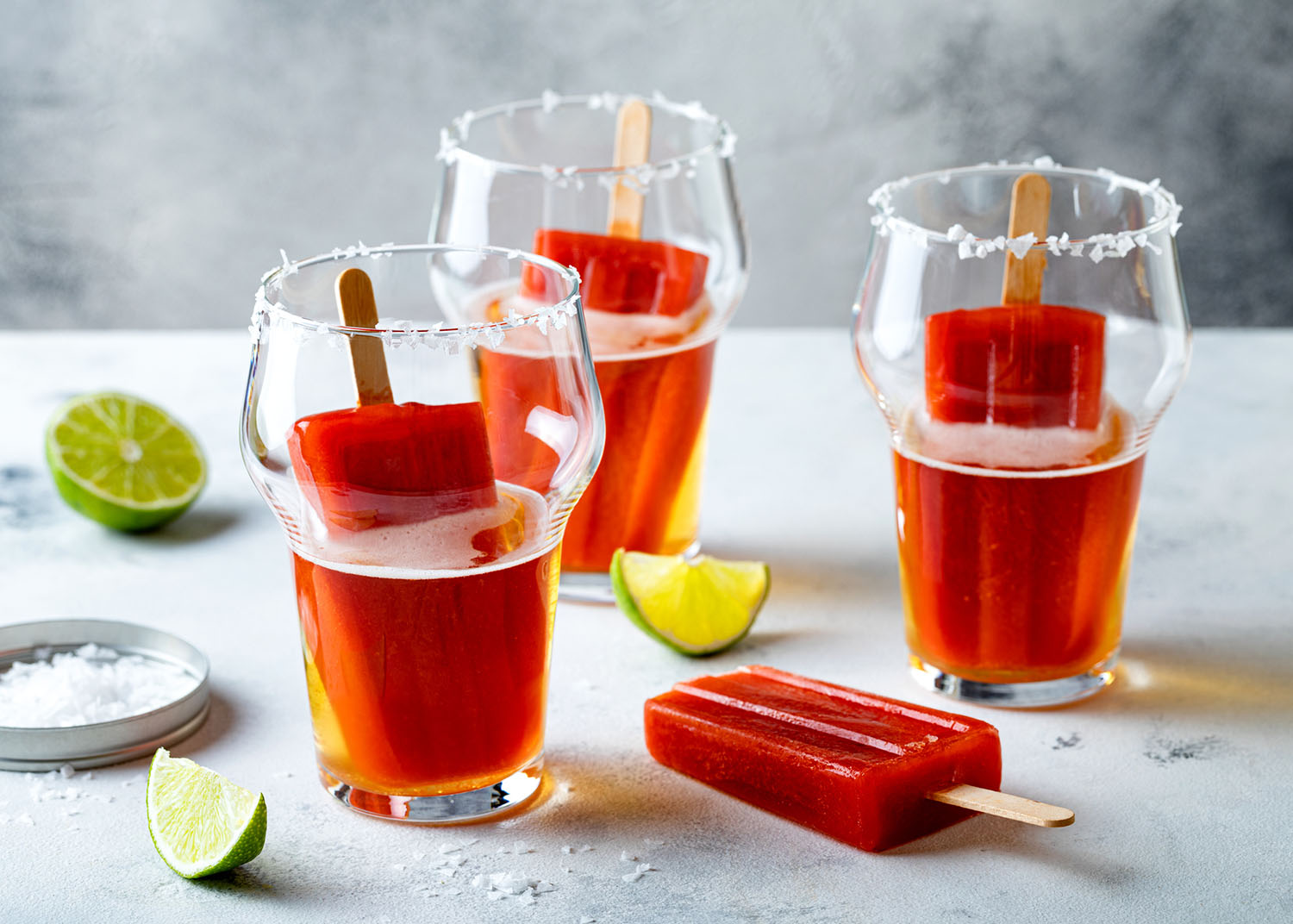 Latin american beer drink Michelada with salt rim and spicy tomato juice popsicles. Summer alcohol cocktail michelada or Mexican bloody beer.
