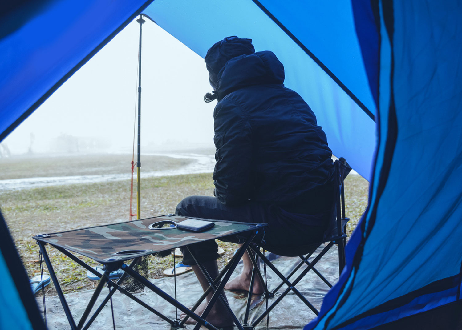 personne attend que pluie cesse dans entrée de la tente avec table