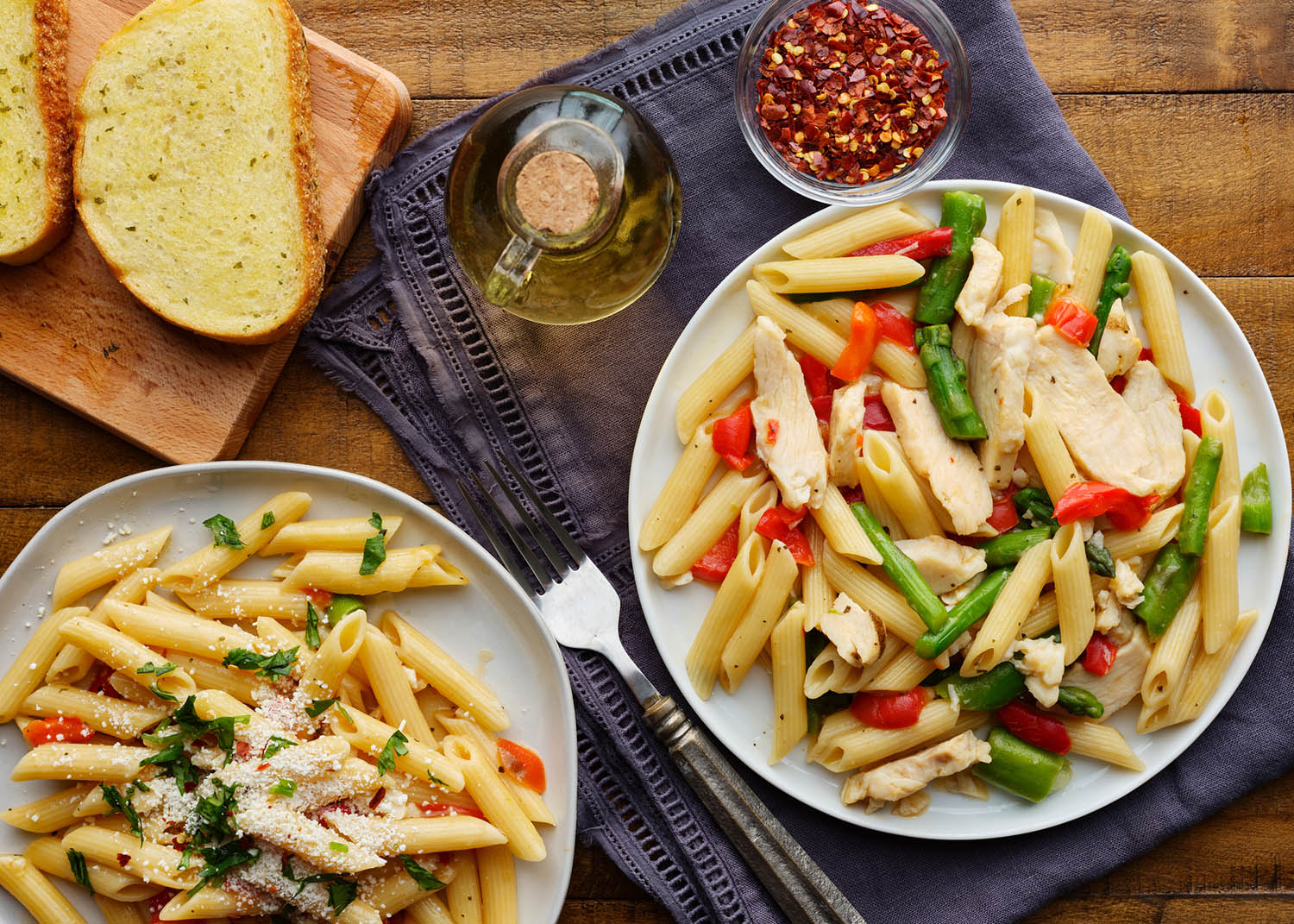 chicken penne pasta with red bell peppers and asparagus top down photo on wooden table