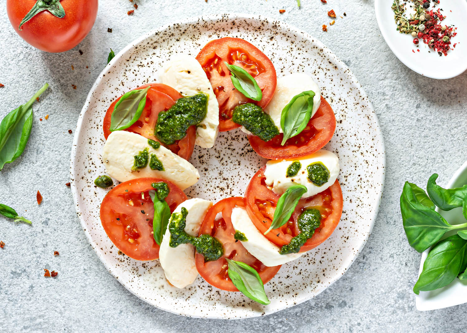 Caprese salad with juicy tomatoes, fresh mozzarella and pesto. Concept for a tasty and healthy appetizer, flat lay. Italian food, cuisine.
