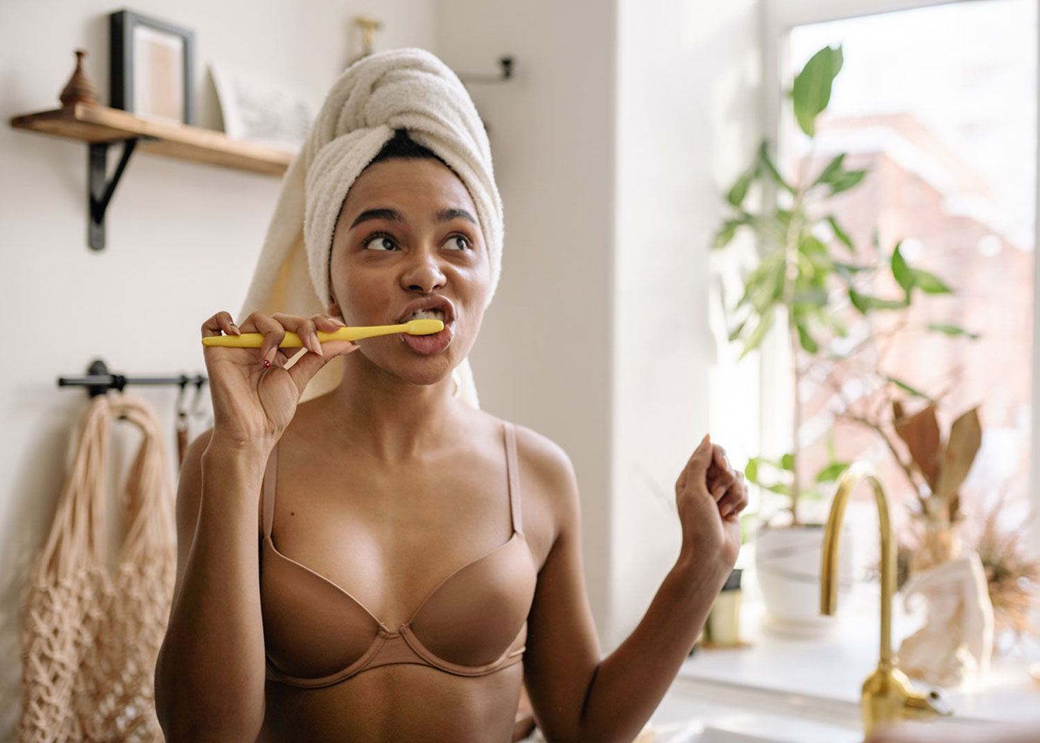 femme se brosse les dents avec serviette sur la tête