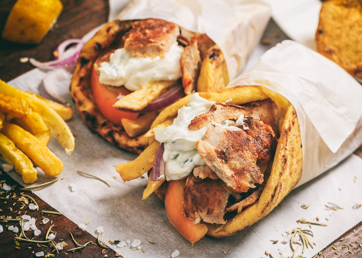 Greek gyros wraped in a pita bread on a wooden background