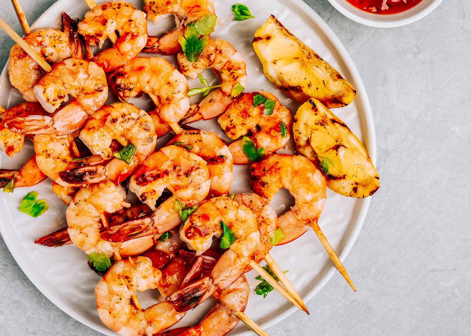 Sweet Chilli Shrimp Skewers with lemon and parsley on gray stone background, top view