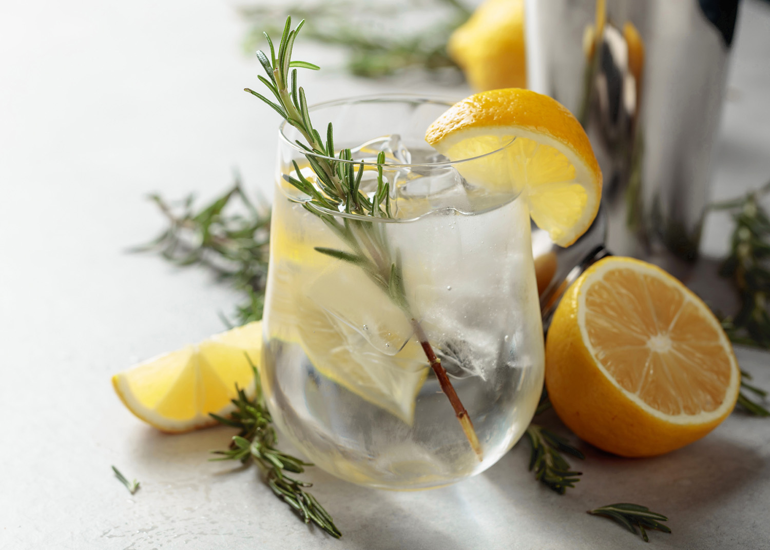 Refreshing drink with natural ice, lemon, and rosemary in a frozen glass. Copy space.