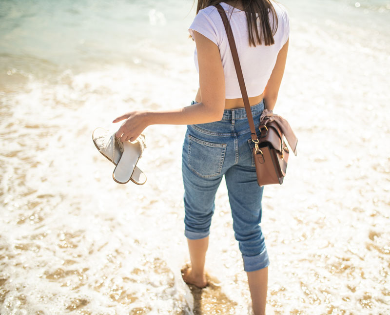 Femme sur la plage avec ses sandales