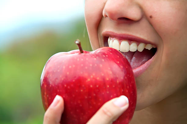 Closeup of a mouth biting a red apple