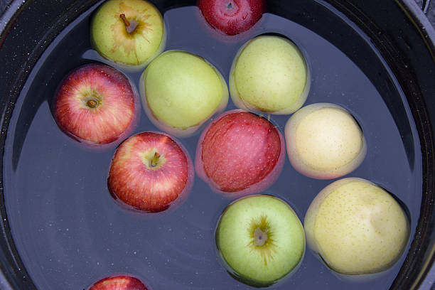 Red and Green Apples Floating in Bucket for Dunking