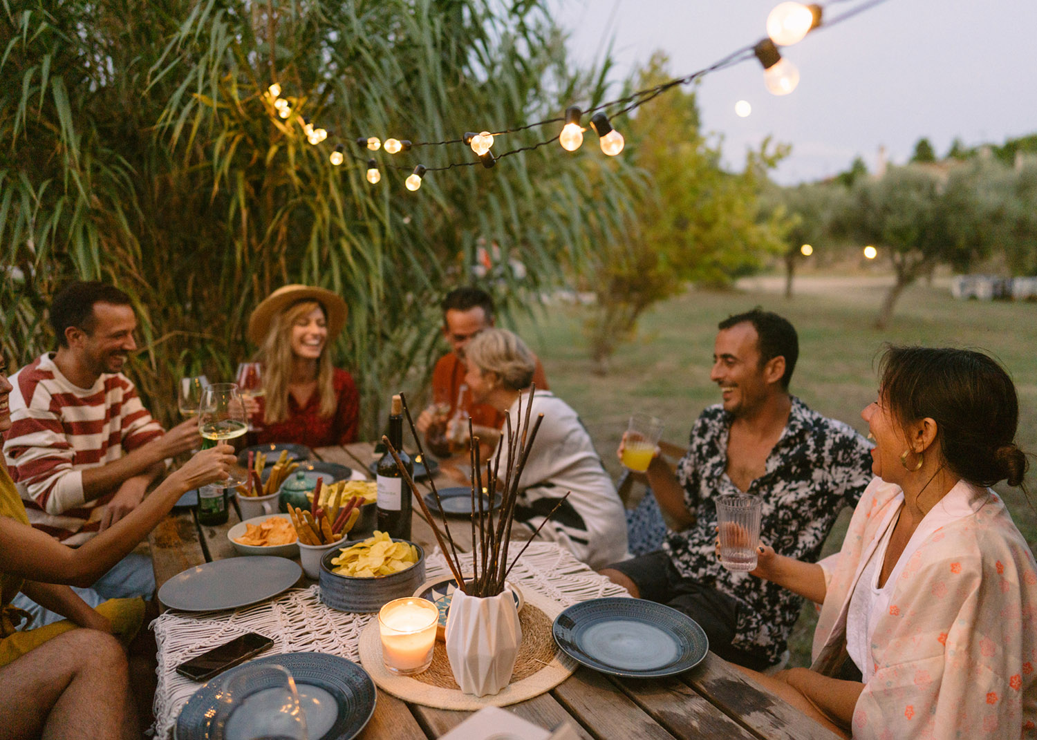 Photo of a small group of friends drinking wine and having fun while enjoying the summer dinner party outdoors.