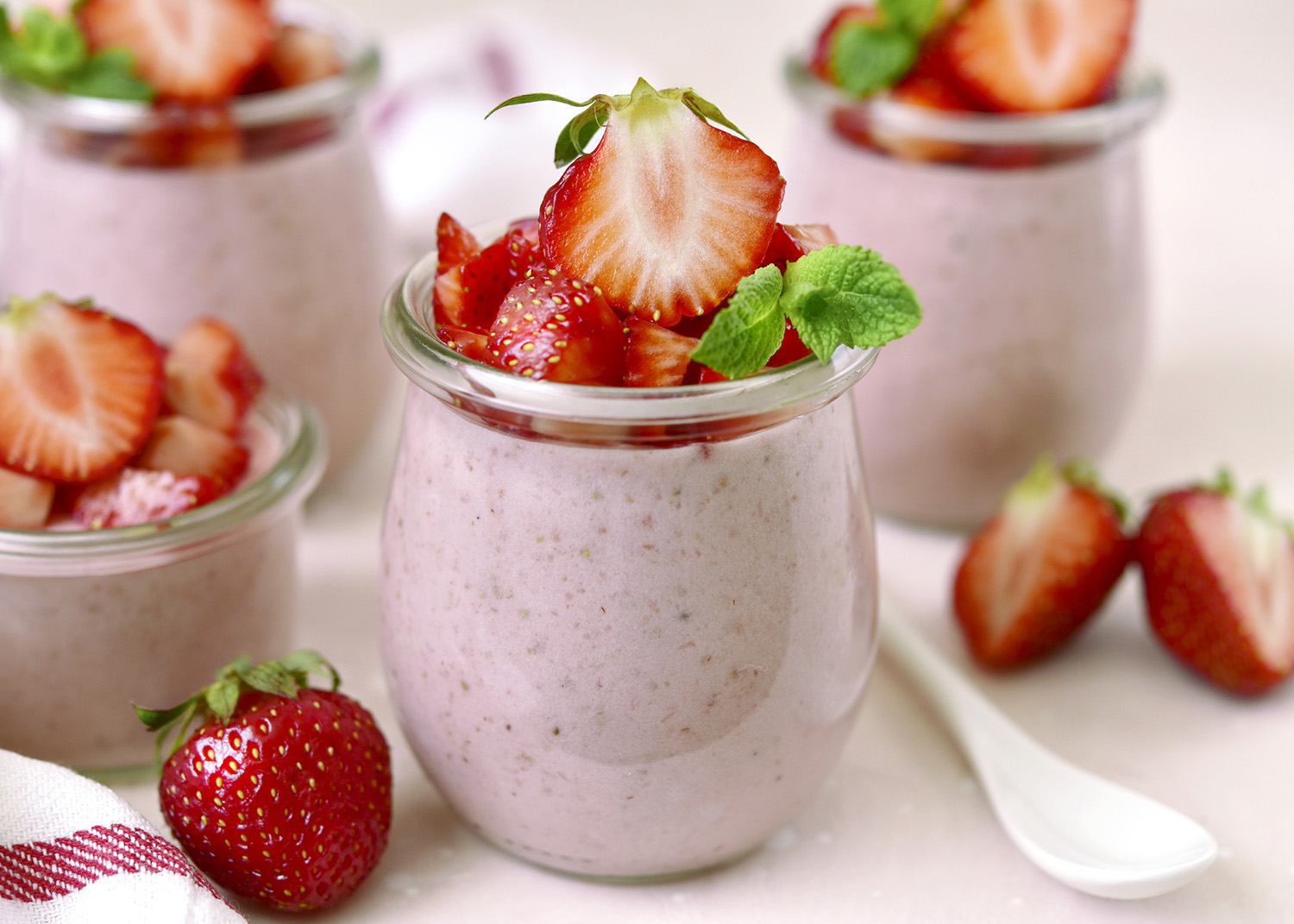 Homemade strawberry mousse in a vintage glass jar on a light slate, stone or concrete background.