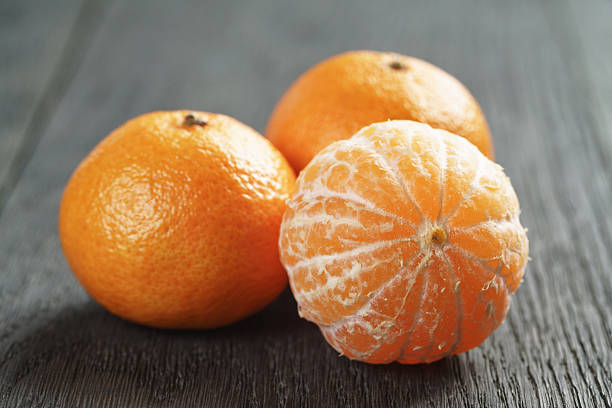 ripe tangerines peeled on wood table, shallow focus