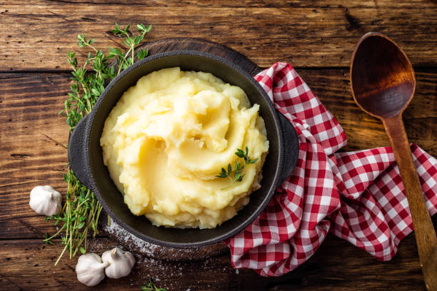 Mashed potatoes, boiled puree in cast iron pot on dark wooden rustic background, top view