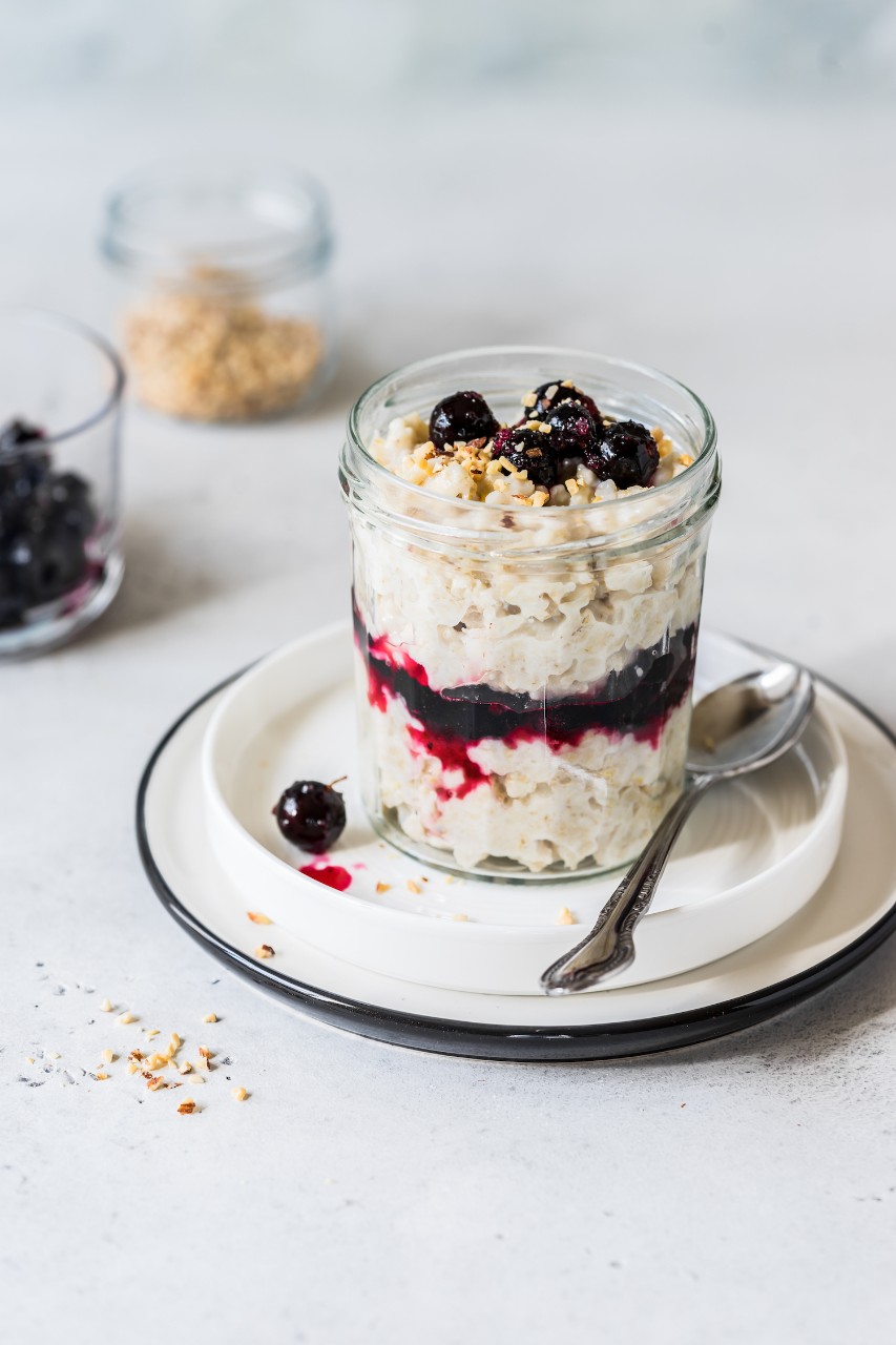 Layered Creamy Oat Porridge in a Jar with Blackcurrants and Chopped Almonds, copy space for your text