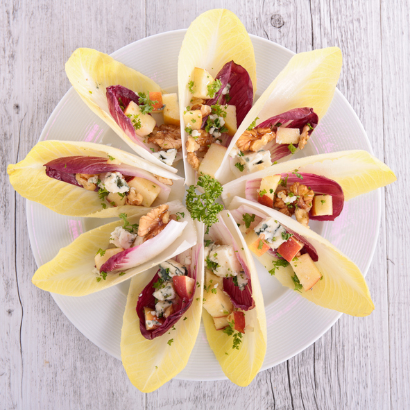 Endive salad with goat cheese, strawberry and walnuts. Belgian endive leaves salad on table
