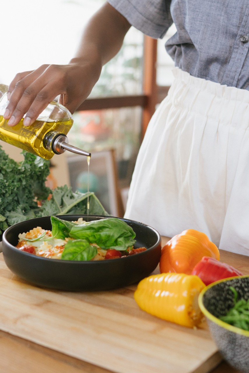 Une femme cuisine avec de l'huile d'olive