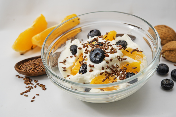 Quark, yogurt or cottage cheese, flax seeds and fresh fruits aug a light gray background, healthy diet for digestion, closeup with selected focus, narrow depth of field