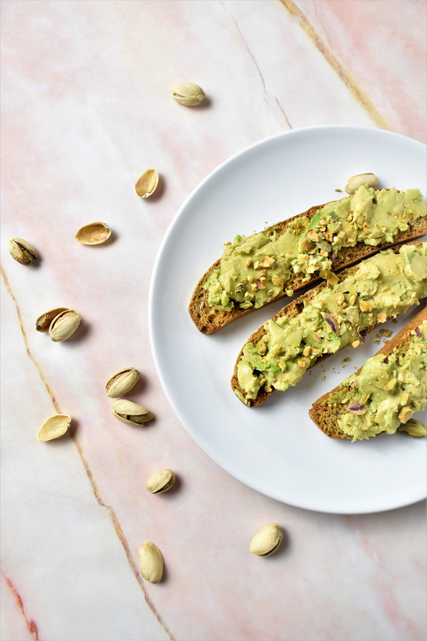 Vegan toast with avocado and nuts on a table, close-up