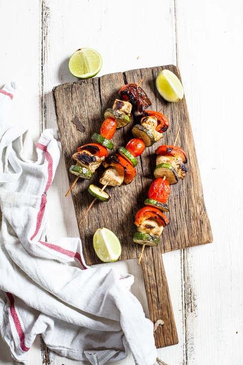 Grill skewers with grilled chicken, tomato, bell pepper and zucchini on chopping board