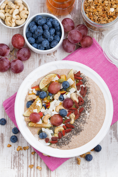 oatmeal with assorted fruits, nuts and chia, top view, vertical