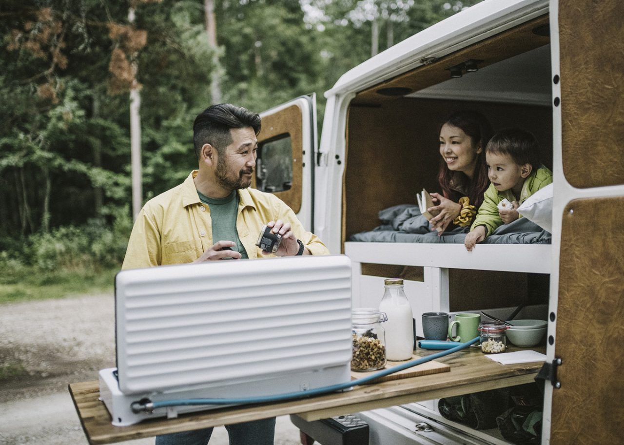 Man making coffee, while camping with his family in a mini van