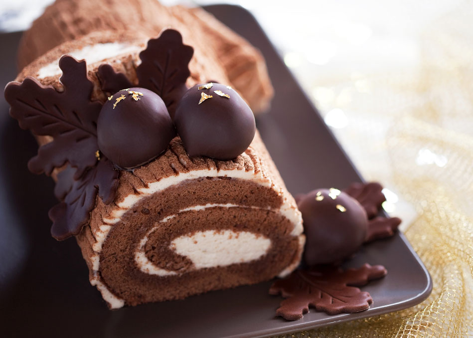 Traditional Christmas Yule Log cake decorated with chocolate chestnuts, selective focus