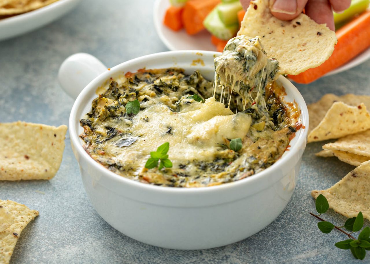 Artichoke spinach dip in a baking dish with a cheese pull