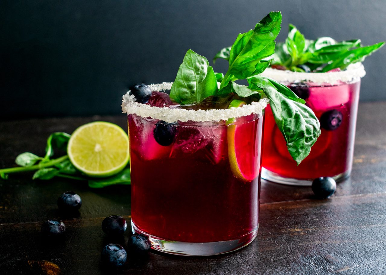Margarita cocktails made with tequila, basil, and blueberries and rimmed with a salt and sugar mixture