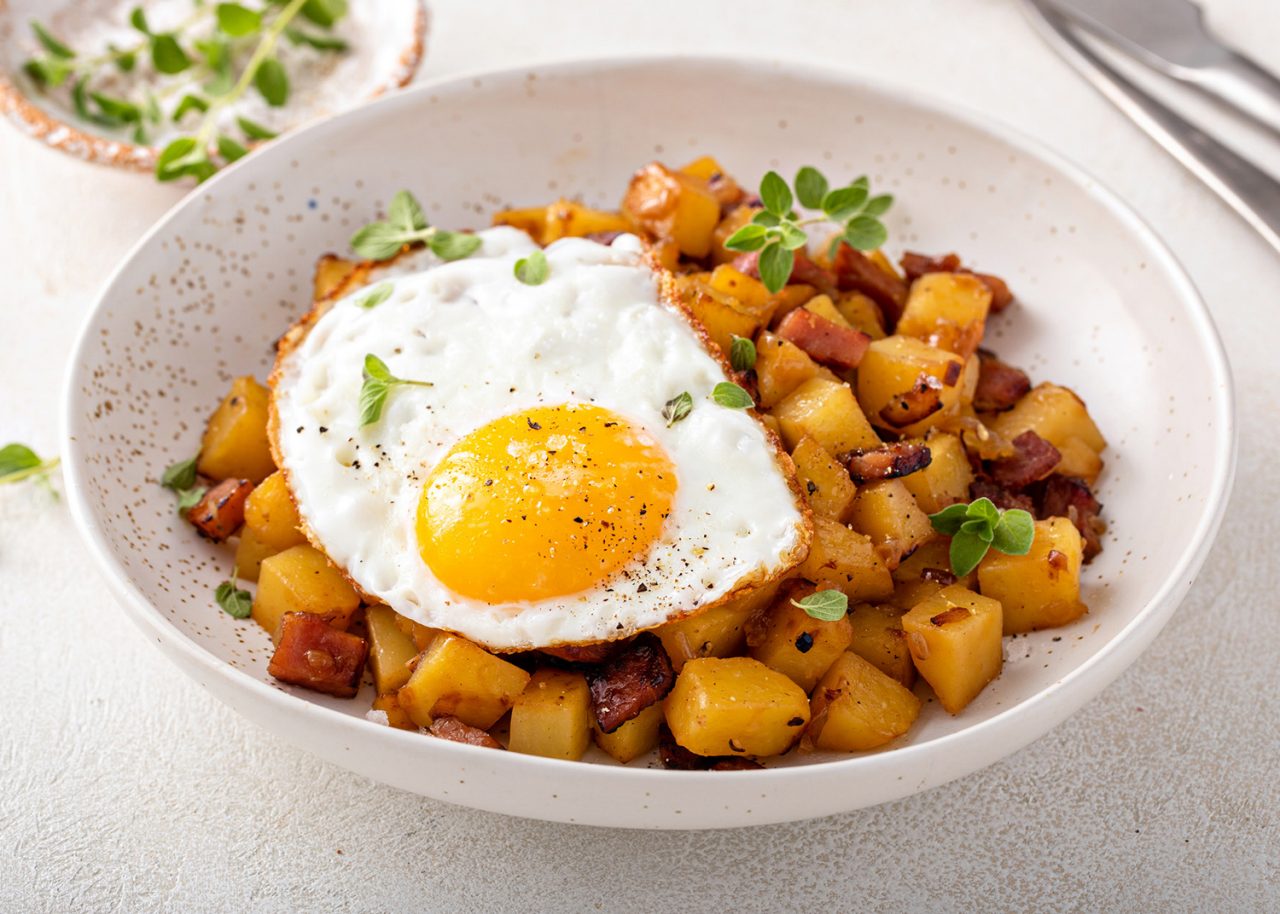 Potato, onion and ham hash for breakfast topped with fried egg