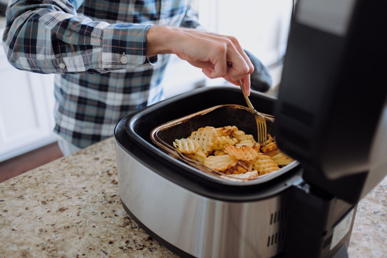 Close-up of unrecognizable white man cooking waffle fries in air fryer