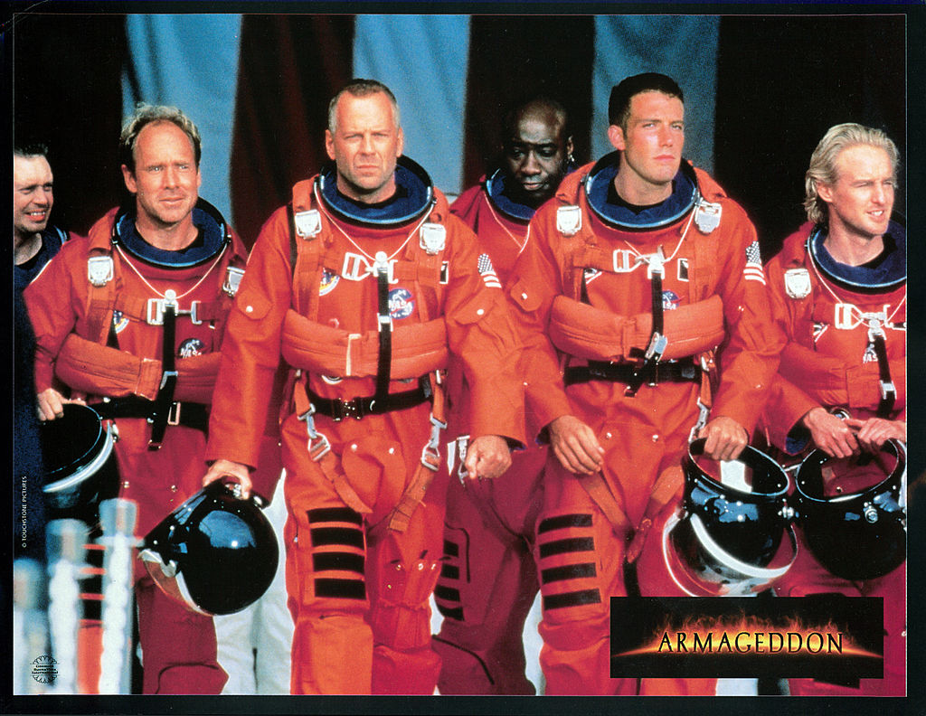 Steve Buscemi, Will Patton, Bruce Willis, Michael Clarke Duncan, Ben Affleck, and Owen Wilson walking in NASA uniforms in a scene from the film 'Armageddon', 1998. (Photo by Touchstone/Getty Images)