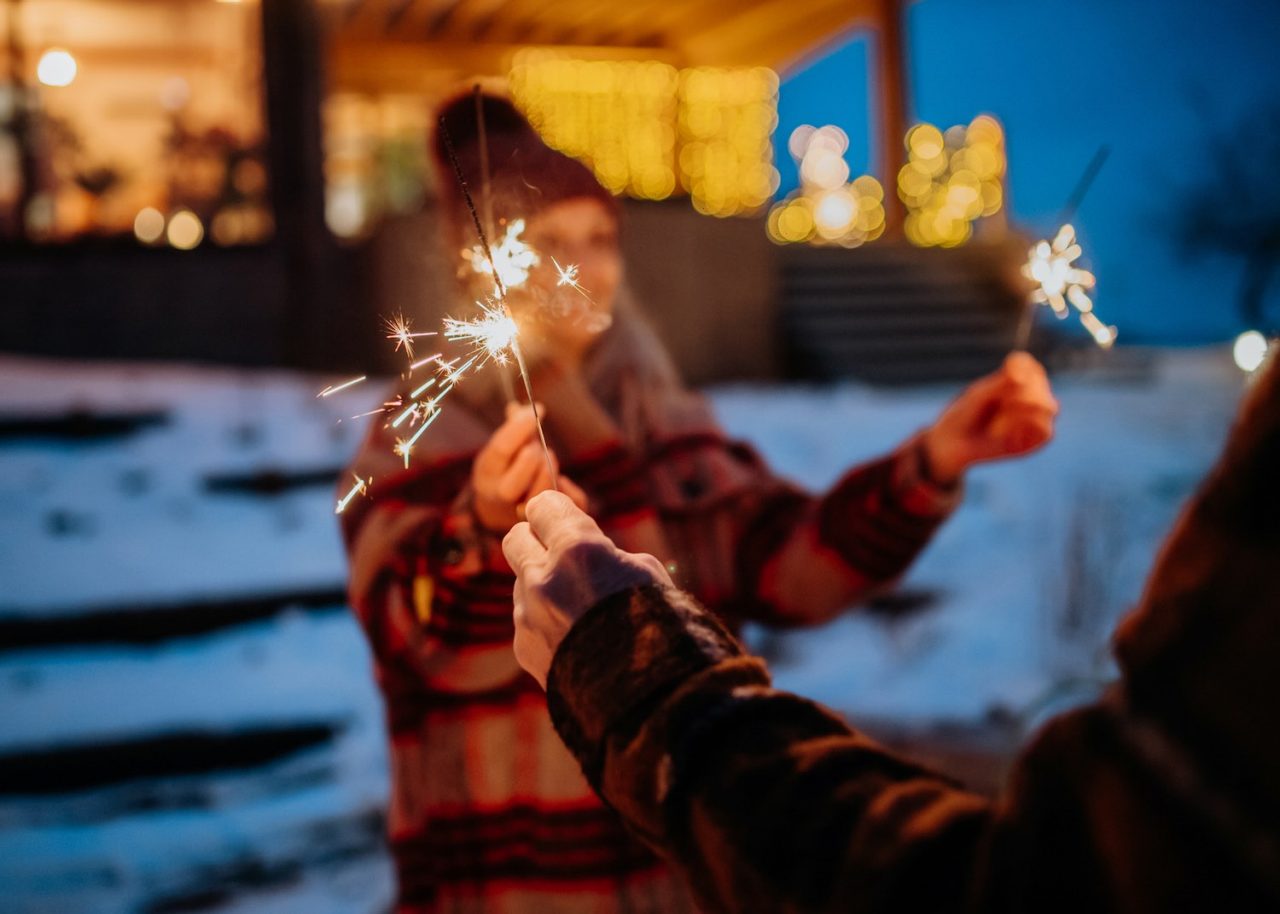 Happy senior couple celebrating new year with the sparklers, enjoying winter evening.