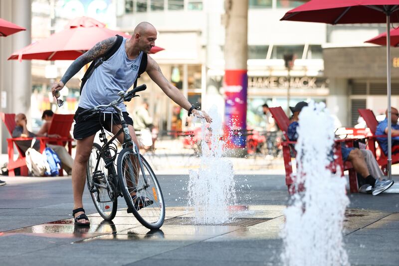 A man cools off in a fountain at Sankofa Square in downtown Toronto amid a heat wave on July 14, 2026. (Cole Burston / The Canadian Press)