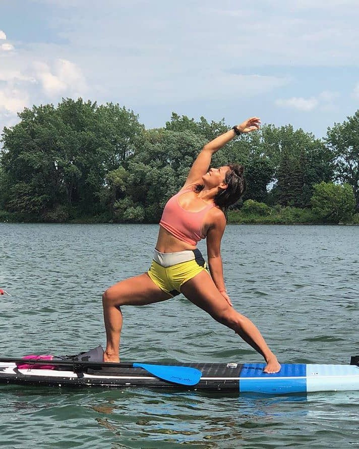 Une femme fait du yoga sur une planche à pagaie