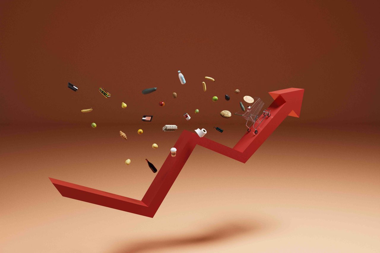 Conceptual image of a shopping cart on an arrow in in an upward trajectory  with foods and groceries falling out, could symbolize ideas around consumer inflation, recession and economic hardship