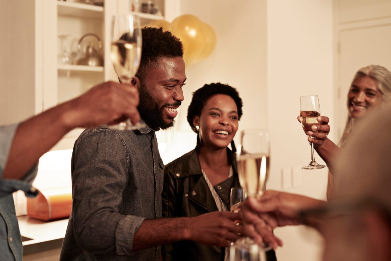 Smiling male and female enjoying champagne during birthday celebration at home