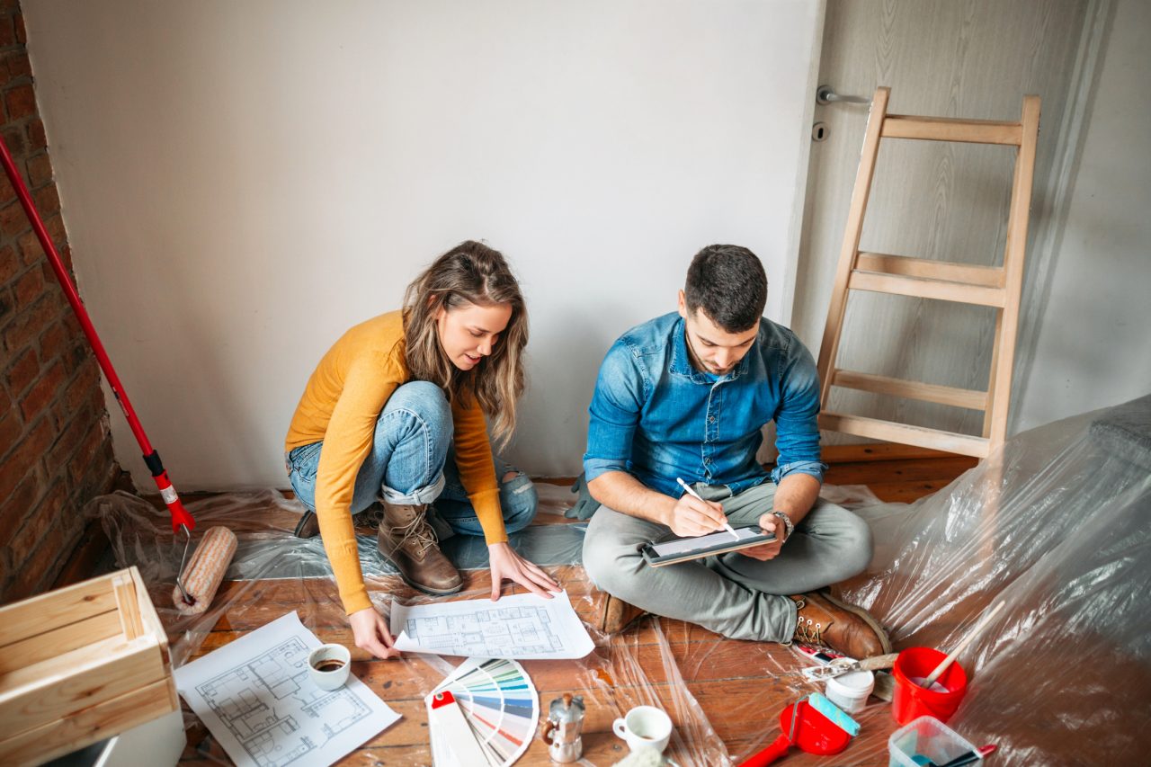 Man and woman choosing the right color for their new living room while sitting on the floor, having a cup of coffee, taking a break from hard work